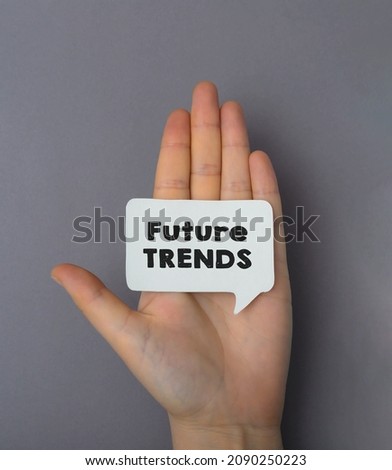 Future trends.Female hand on a gray background holds a card with text. Conceptual photo.