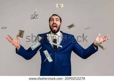 Rich lucky bearded man screaming yes i did it, joyful reacting to success, victory, money rain falling from up, celebrating, wearing official style suit. Indoor studio shot isolated on gray background Royalty-Free Stock Photo #2090252278
