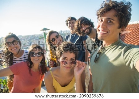 Funny friends taking selfie at party. People of different nationalities holding brown bottles, making faces. Taking pictures with phone. Party, friendship, social media concept