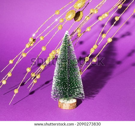 New Year's tree with golden decorations on a purple background. Minimal Christmas idea.