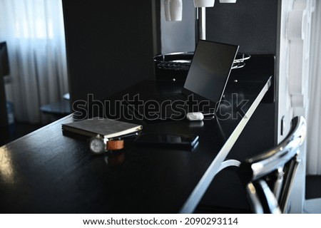 Office accessories, laptop, earphones on the box, watch, mobile phone and gray notepad on wooden table at home kitchen