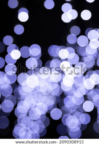 Very Peri trend color of the year 2022 bokeh background effect. Defocused blur golden toned colour light bulbs garlands. Christmas New Year party holiday concept. 
