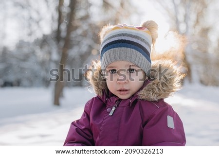 toddler girl in winter snowy forest playing with snow. Sunny winter day. Frosty snowy winter.