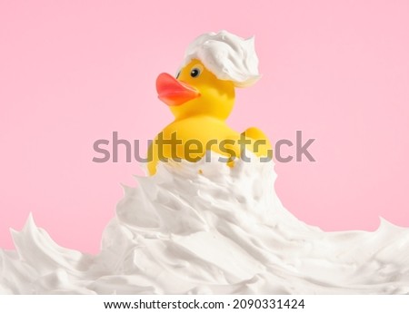 Yellow rubber duck swim on crest of foam wave on pink background. Positive idea shower and relax.