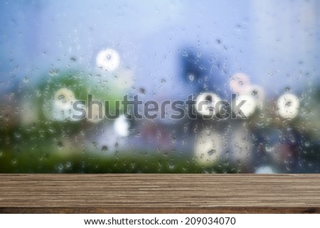Wooden desk with water drops windows background
