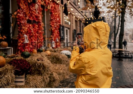 Man in yellow raincoat takes pictures of halloween decor
