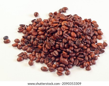 Coffee beans isolated on white background. Pile of roasted coffee beans scattered on white table.