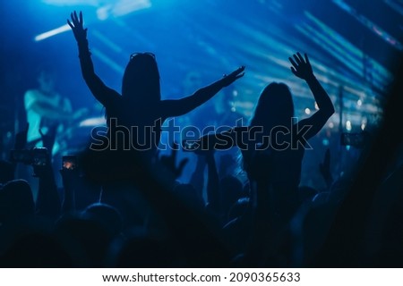 Two girls in a audience crowd having fun and enjoying concert on a festival