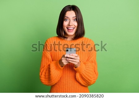 Portrait of attractive cheerful amazed girl using gadget social network post isolated over bright green color background