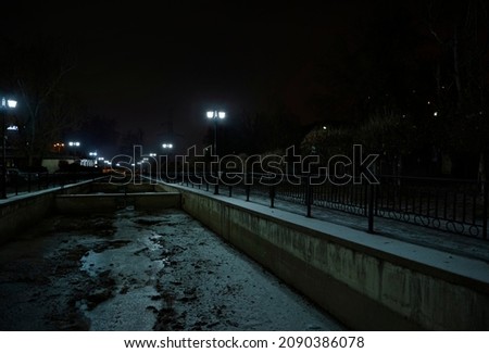 Dried riverbed illuminated by the lanterns of the embankment at night in winter.