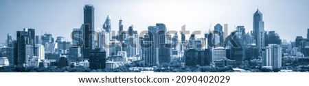 Blue-filtered cityscape and high-rise buildings in metropolis city center . Downtown business district in panoramic view .