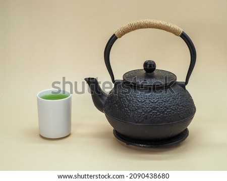 Cast Iron Tea Kettle with Cup of Natural Green Tea