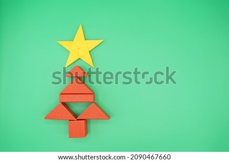 Christmas theme with red blocks forming a Christmas tree and red paper folded into a pentagram. Green background.