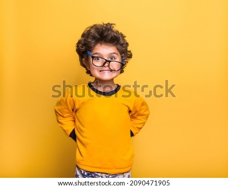 Funny surprised little child boy in glasses looking in camera isolated on yellow background. Kindergarden kid smiling. Education for smart children. Royalty-Free Stock Photo #2090471905