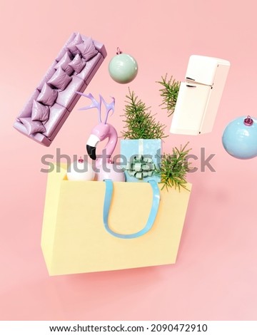 Creative Holiday Christmas shopping yellow bag full of home furniture presents, New year trees, decoration balls. Pastel pink background.