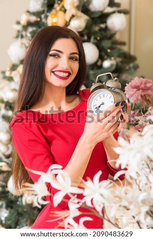 Young brunette woman with a smile near the Christmas tree.