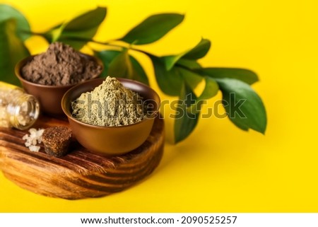 Bowls with henna powder on color background