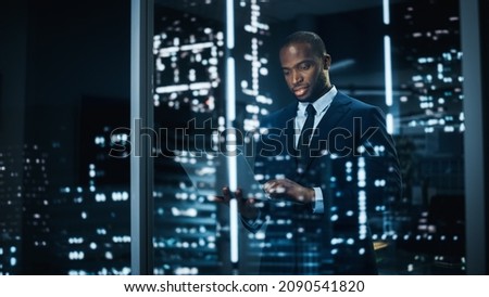 Portrait of Stylish Black Businessman Using Laptop, Looking out of Window on a City. successful African-American CEO Working on Computer, Working Hard Late At Night to Achieve Best Results Royalty-Free Stock Photo #2090541820