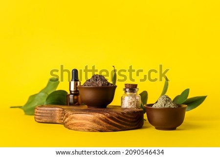 Bowls with henna powder, sea salt and essential oil on color background