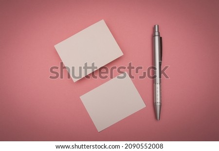 blank business card on pink background with a pen