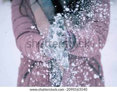 Young woman throwing snow in the air at sunny winter day,Outdoor waist up portrait,winter and christmas atmosphere,photo in snowy nature