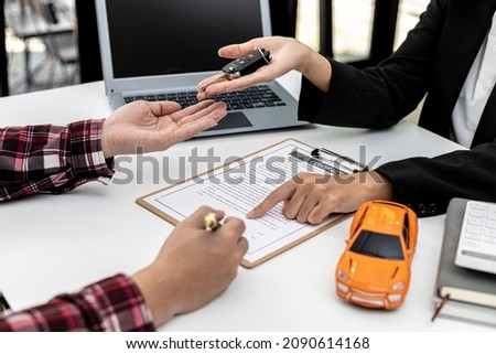 The renter is signing a car rental agreement with the car rental company. After discussing the details and charges with the employee, the employee hand over the car keys to the renter. Royalty-Free Stock Photo #2090614168