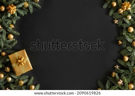 Christmas banner with gold gift, baubles, evergreen nobilis branches on black background with copy space. Xmas greeting card. Happy New Year. View from above, flat lay.