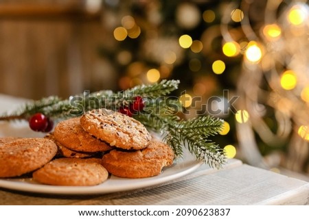 Recipe delicious homemade handmade pastries kitchen home.Christmas tree with decor yellow bokeh light.Sweet oatmeal cookies with sesame seeds plate table.Happy New Year.Merry Christmas.selective focus