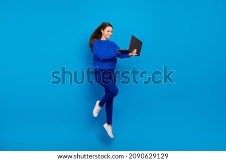 Full length body size view of attractive cheerful girl jumping using laptop isolated on bright blue color background