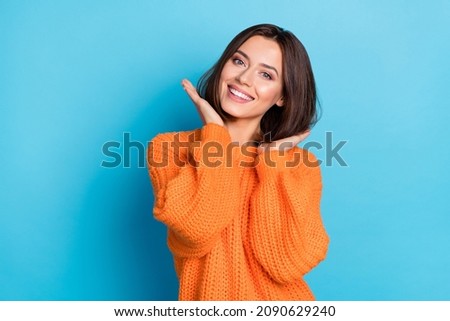 Portrait of attractive cheerful well-groomed girl touching soft smooth hair isolated over bright blue color background