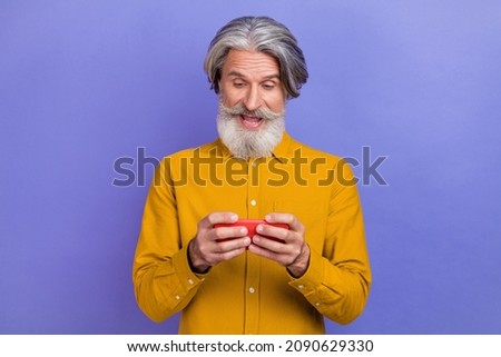 Photo of excited senior man play game mobile weekend race speed addicted isolated over purple color background