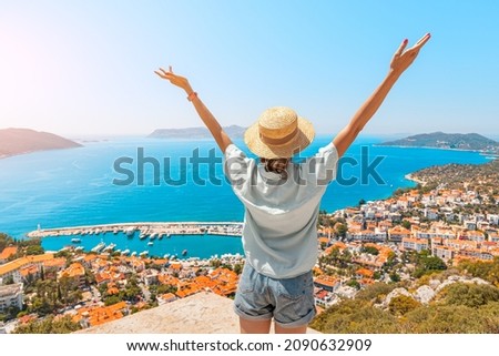Happy woman with open arms stands on the viewpoint and enjoys the panorama of Kas resort town of the Mediterranean sea in Turkey Royalty-Free Stock Photo #2090632909
