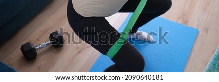 Woman doing squats with rubber band at home