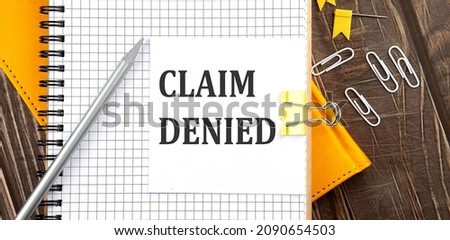 CLAIM DENIED text on a sticker on notebook, wooden background