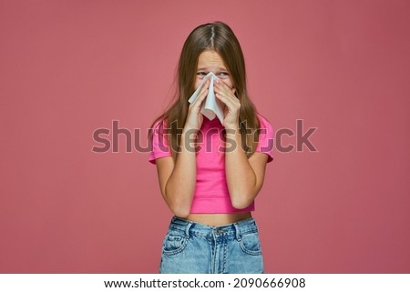 Sick girl child cry, blowing runny nose, sneezing in tissue, suffer seasonal allergy or flu symptoms on pink background Royalty-Free Stock Photo #2090666908
