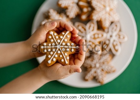 Ginger Christmas cookies in children's hands on the background of the Christmas tree.