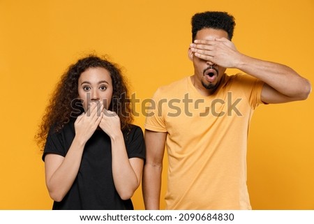 Young couple two sad friends family shocked african man woman together in black t-shirt cover mouth with hand put arm on face facepalm epic fail gesture isolated on yellow background studio portrait