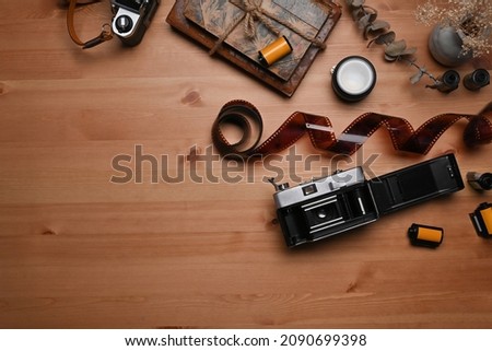 Top view vintage books, film rolls and retro camera on wooden table.