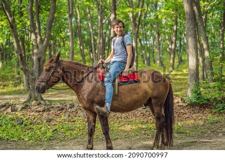 handsome man ride on the black horse in green forest