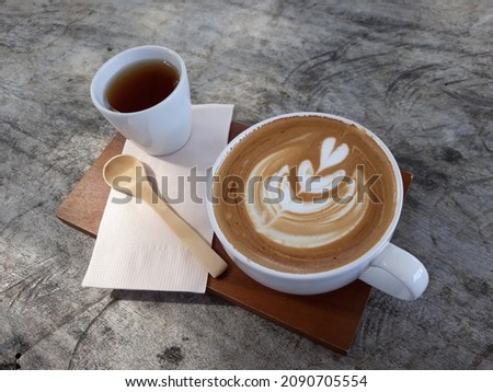 Top view of hot coffee, cappuccino with beautiful pattern makeup and tea set on wooden table.