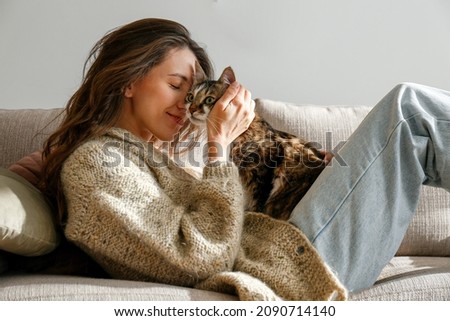 Portrait of young woman holding cute siberian cat with green eyes. Female hugging her cute long hair kitty. Background, copy space, close up. Adorable domestic pet concept. Royalty-Free Stock Photo #2090714140