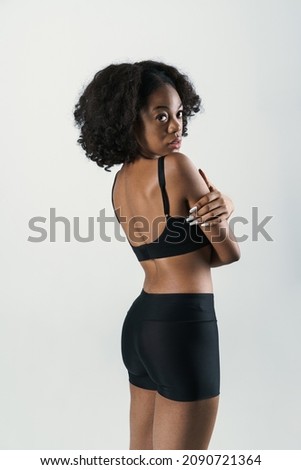 Young black woman in sportswear posing and looking at camera isolated over white background