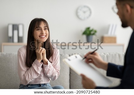 Successful therapy. Cheerful arab woman talking to psychologist on meeting in office, sharing her progress with doctor, receiving professional help at clinic
