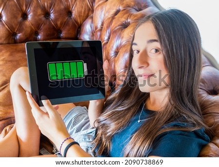 Teenager adolescence girl holding a tablet fully charged. Student at home. Battery life and charging. Royalty-Free Stock Photo #2090738869