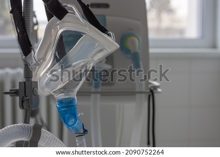 Non-invasive ventilation face mask, side view, on background medical ventilator in ICU in hospital. Royalty-Free Stock Photo #2090752264