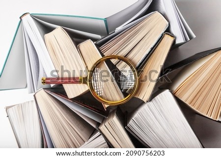 Magnifier over different books. Concept of knowledge, research and studying.