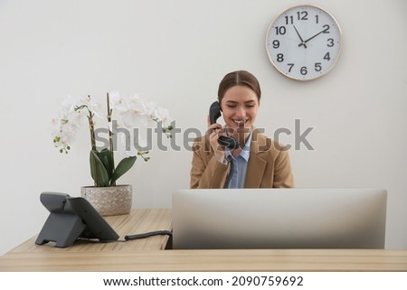 Beautiful receptionist talking on phone at counter in hotel Royalty-Free Stock Photo #2090759692