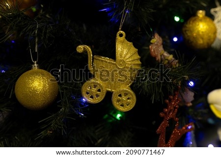 Christmas tree toy on the Christmas tree symbolizing a pram with a baby and the inscription Baby's First Christmas