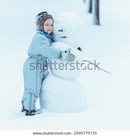 Little cute boy builds a snowman on a winter day.
