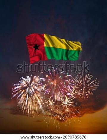 Holiday fireworks in evening sky and flag of Guinea Bissau for National Independence day
